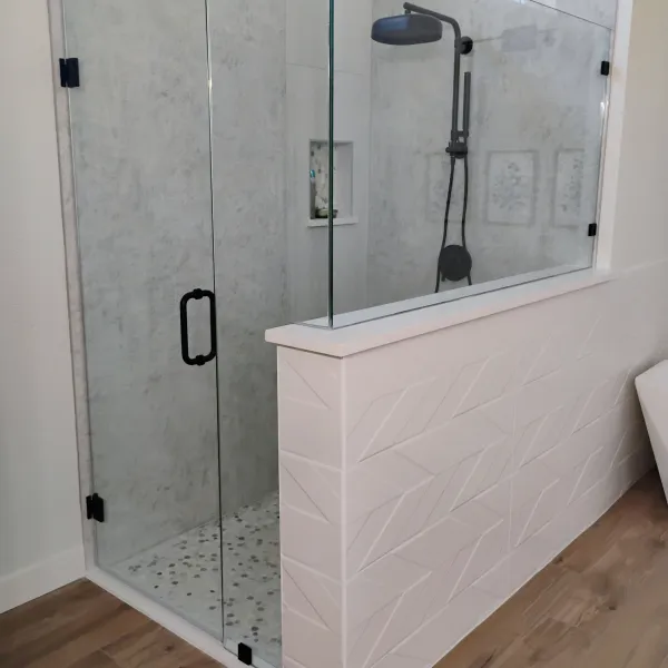 Frameless shower door on a chevron-tile half wall
