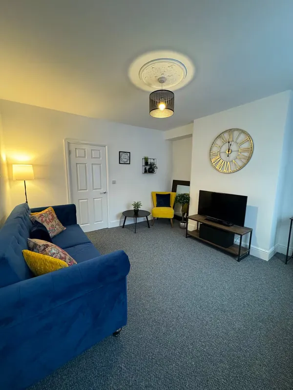 Living room with blue sofa and wall clock at the Barnsley town centre home
