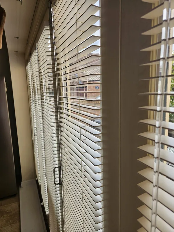 Cream wood venetian blind slats tilted for privacy on a bi-fold door, fitted by Eclipse SBC in Woodhall Spa