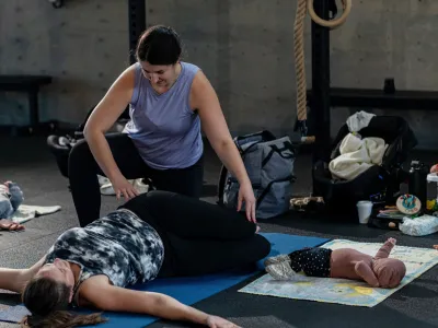 A coach guiding a floor exercise in the postpartum class