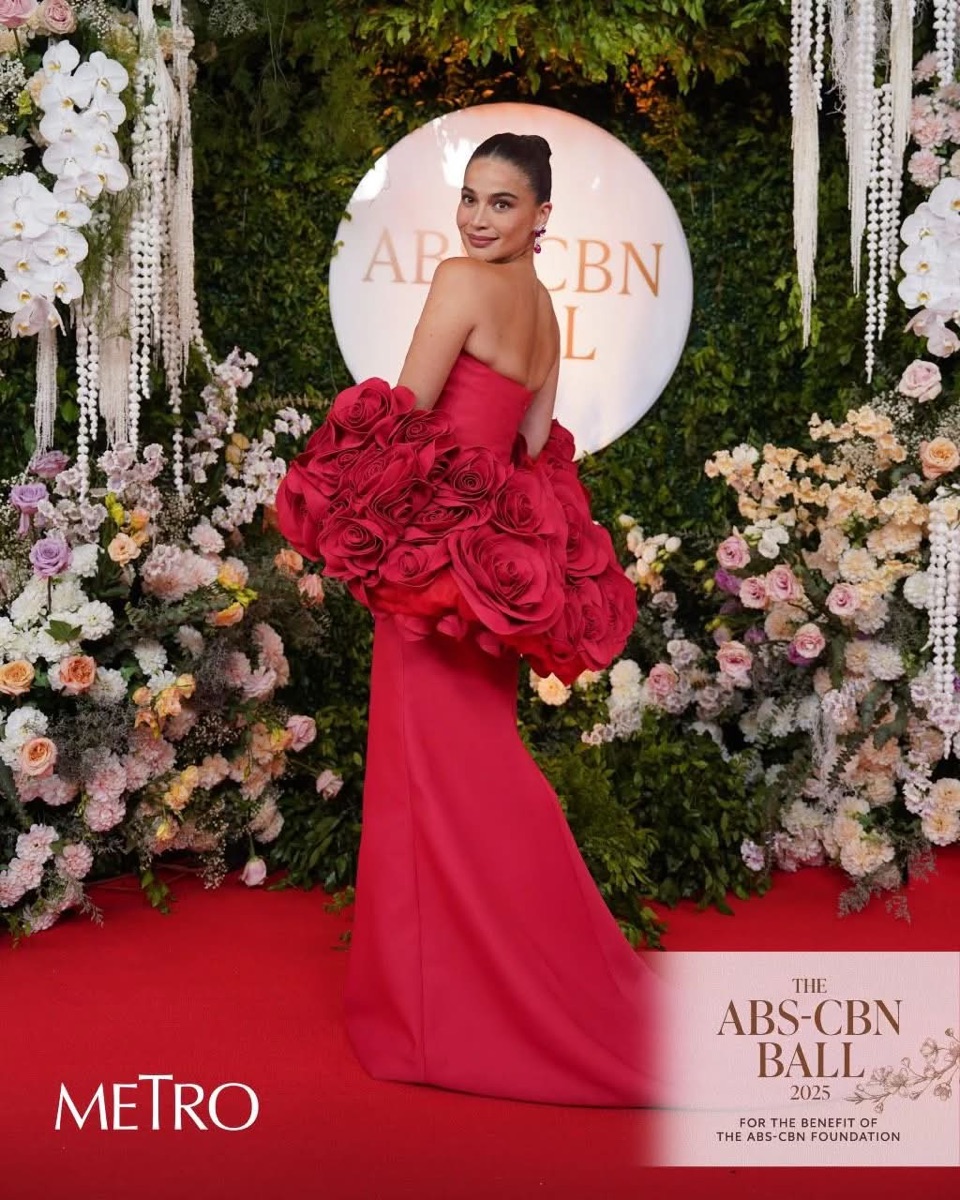 A red strapless gown with sculpted roses on a red carpet