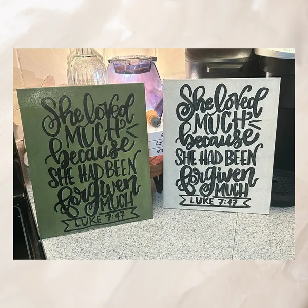 Two student hand lettered signs on green and white canvases