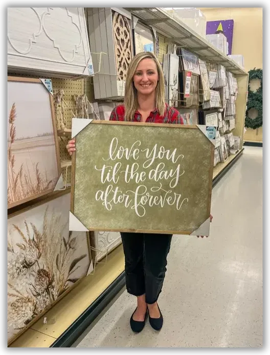 Danielle holding her hand-lettered sign on the shelf at Hobby Lobby