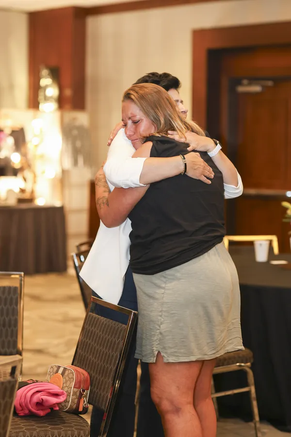 Two women sharing a hug at a gathering