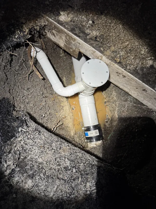 White drainage inspection fitting in an excavated pit