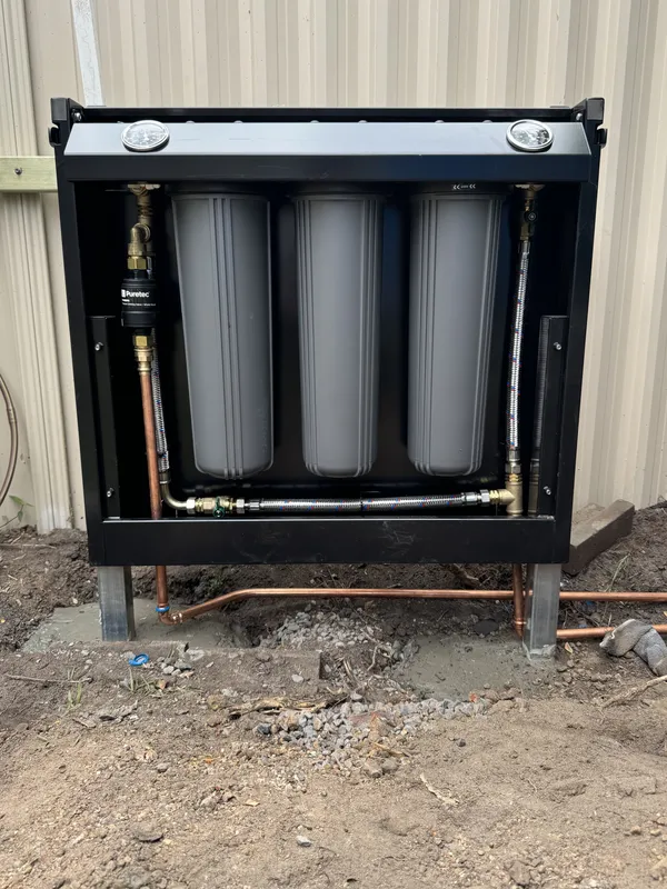 Open filtration cabinet with three filter cartridges and copper pipework