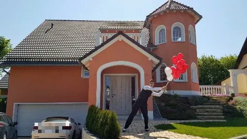 Frank Kraeh springt mit roten Herz-Luftballons vor seinem Haus in Schneeberg