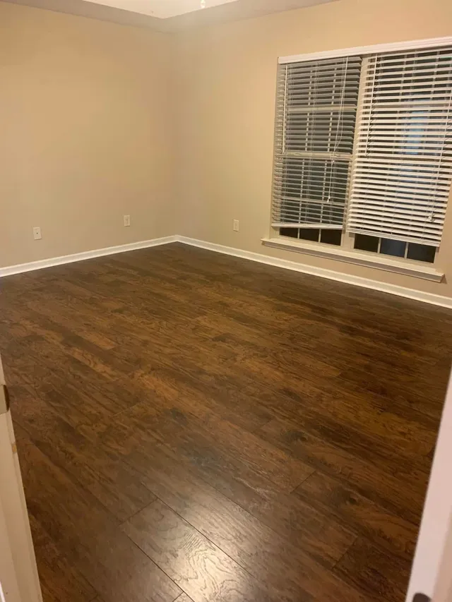 Empty bedroom with wood floors and blinds dusted by Pretty in Pink Cleaning Service near Tallassee, AL