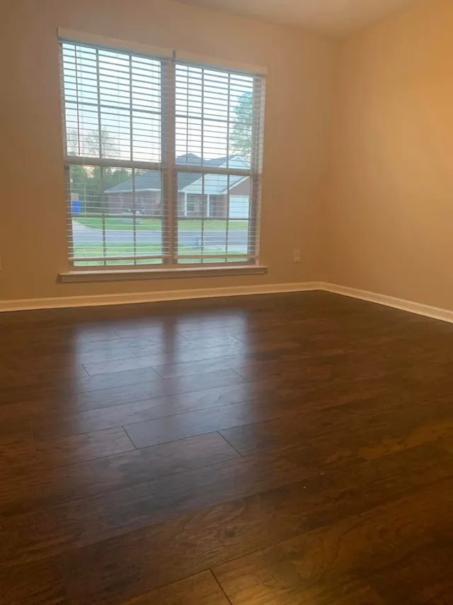Bright bedroom with wood floors and a large window cleaned by Pretty in Pink Cleaning Service near Eclectic, AL