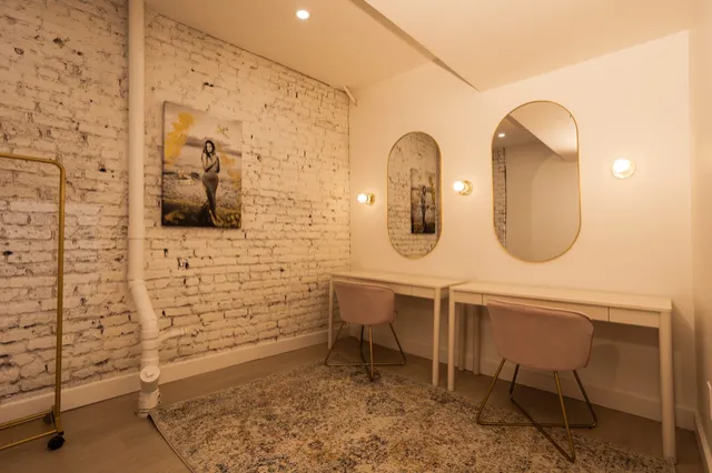 Coin beauté avec coiffeuses, miroirs dorés et mur de briques blanches