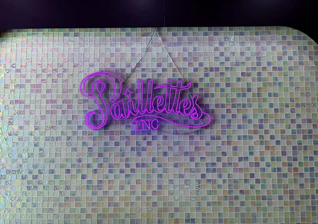 Enseigne néon Paillettes sur le mur de mosaïque irisée