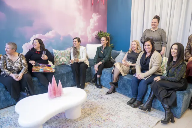 Groupe de femmes réunies dans le coin lounge, devant la murale de nuages roses