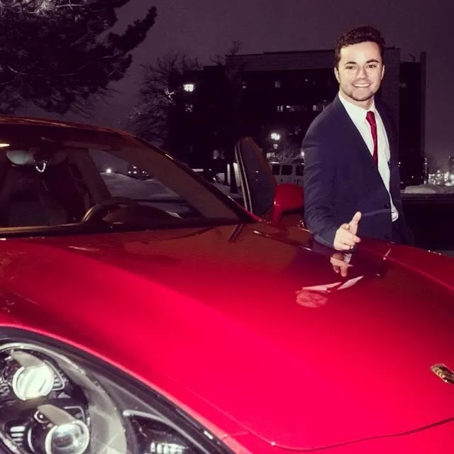 Avi Grondin in 2017, in a suit beside a red sports car at his valet company