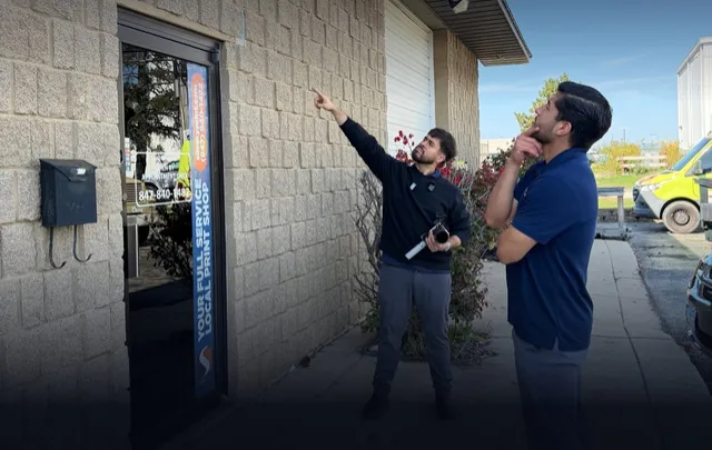Angel and Cesar from VELPI looking up at the sign of a local business