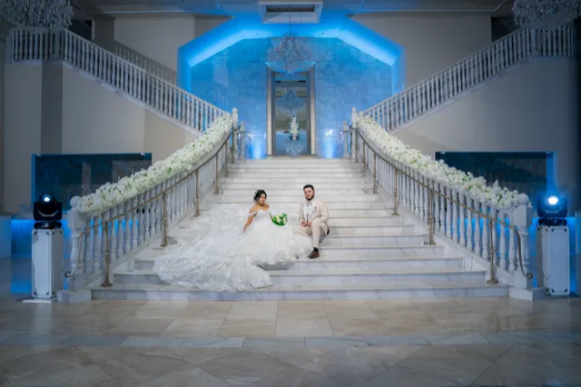 Novios sentados en la gran escalera de un salón con iluminación azul