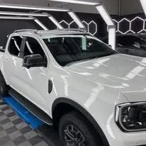 A white truck is parked on a lift in a garage - window tinting by Tint Wright Brisbane