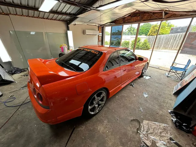 An orange car is parked in a garage - window tinting by Tint Wright Brisbane