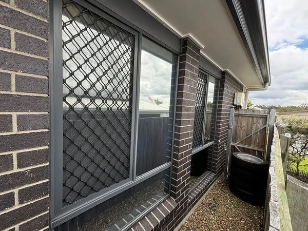 A brick building with a fence and a window - window tinting by Tint Wright Brisbane