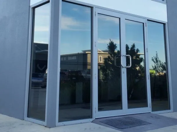 A building with a reflection of trees in the windows - window tinting by Tint Wright Brisbane