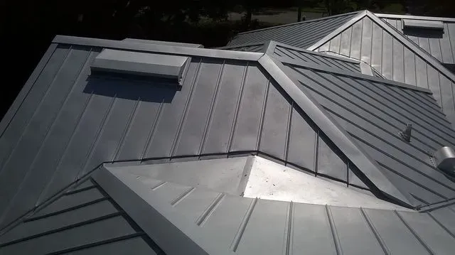Close-up of a dark standing seam metal roof with a roof vent