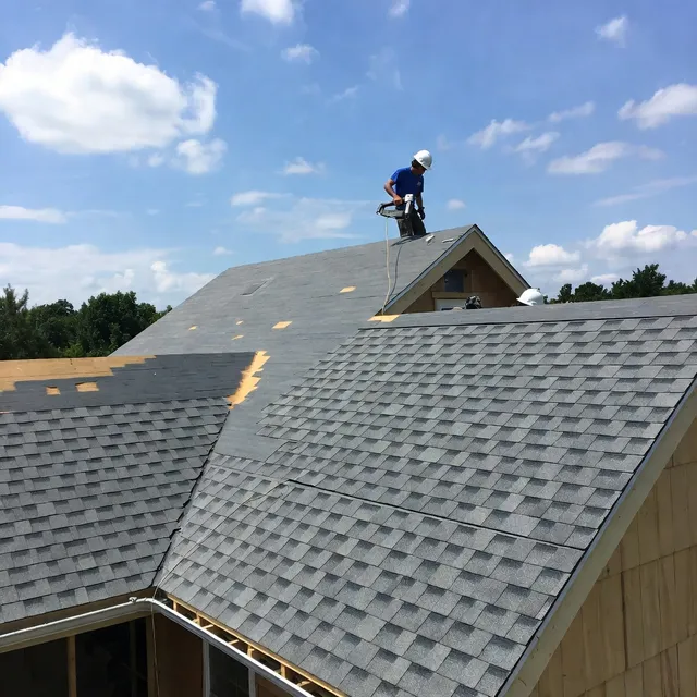 Roofer installing new shingles over underlayment on a shingle roof installation