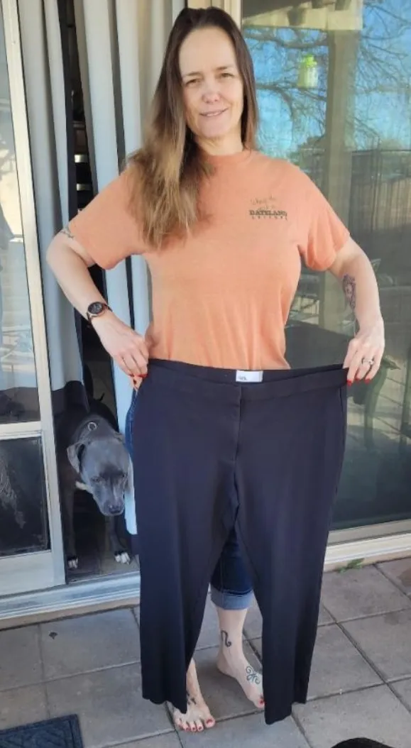 Single original archive photograph of a woman holding a pair of trousers; not a paired before-and-after comparison