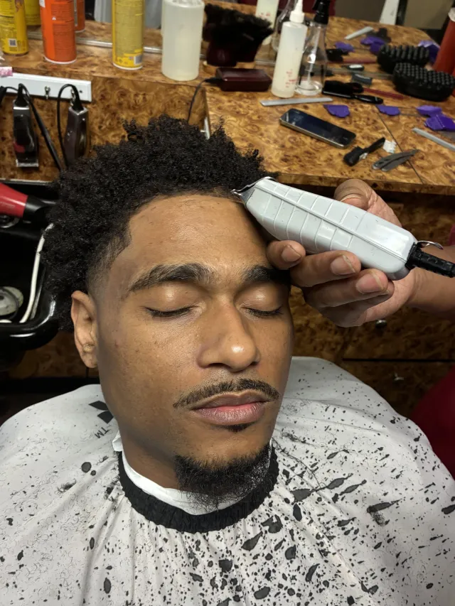 Barber running clippers along a client's hairline for a clean line-up