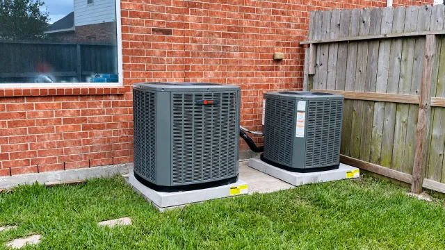 Two outdoor Trane air-conditioning units beside a brick home