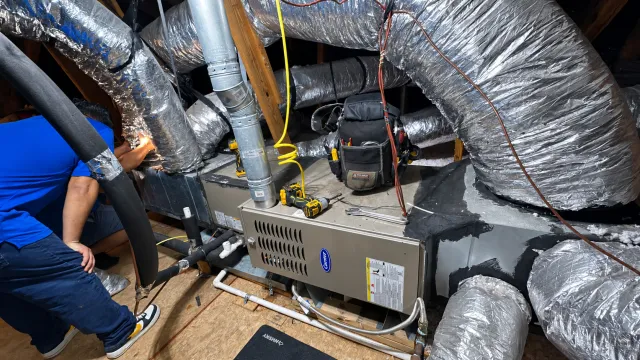 Al’s technician working beside an attic HVAC system