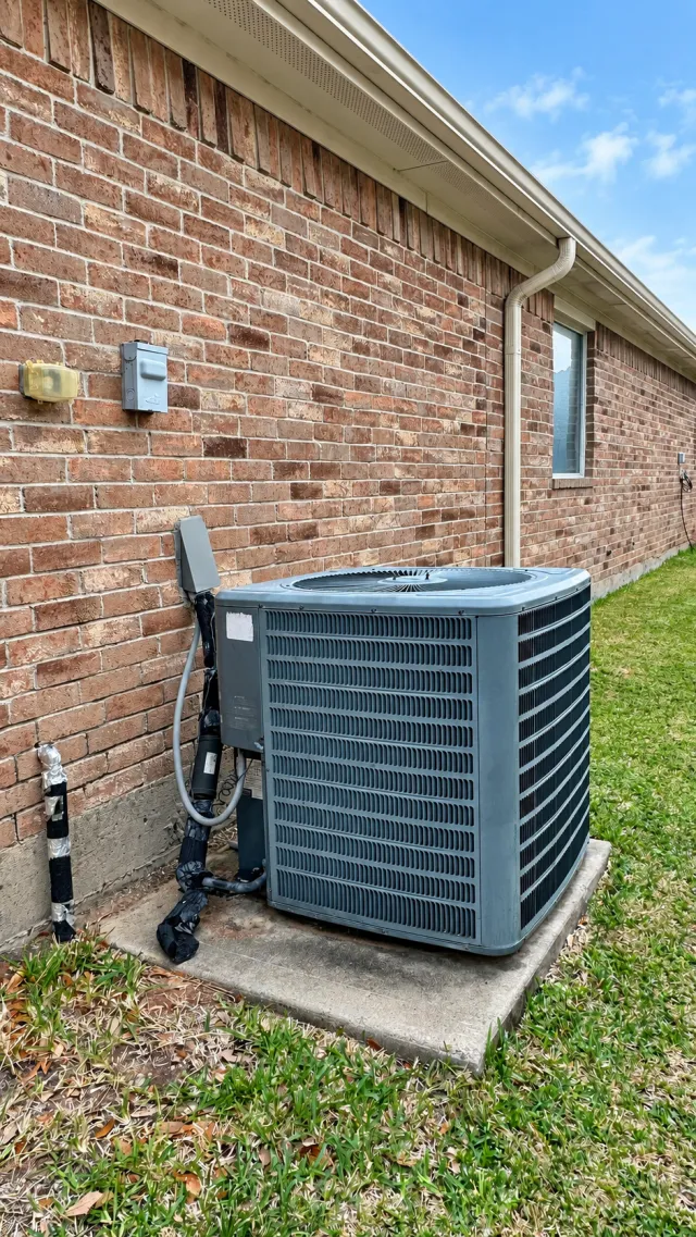 Outdoor air-conditioning condenser beside a brick home