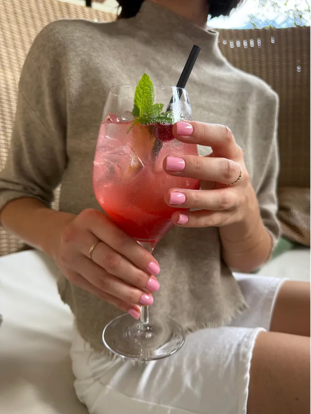 Pink press on nails holding a glass