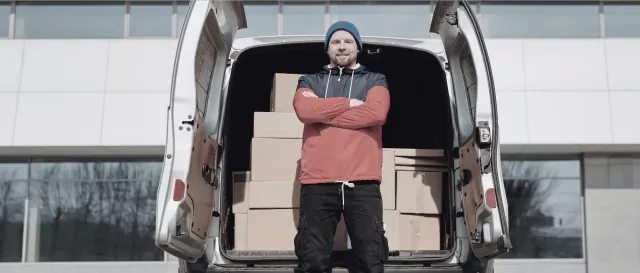 A worker standing at the open rear of a commercial van