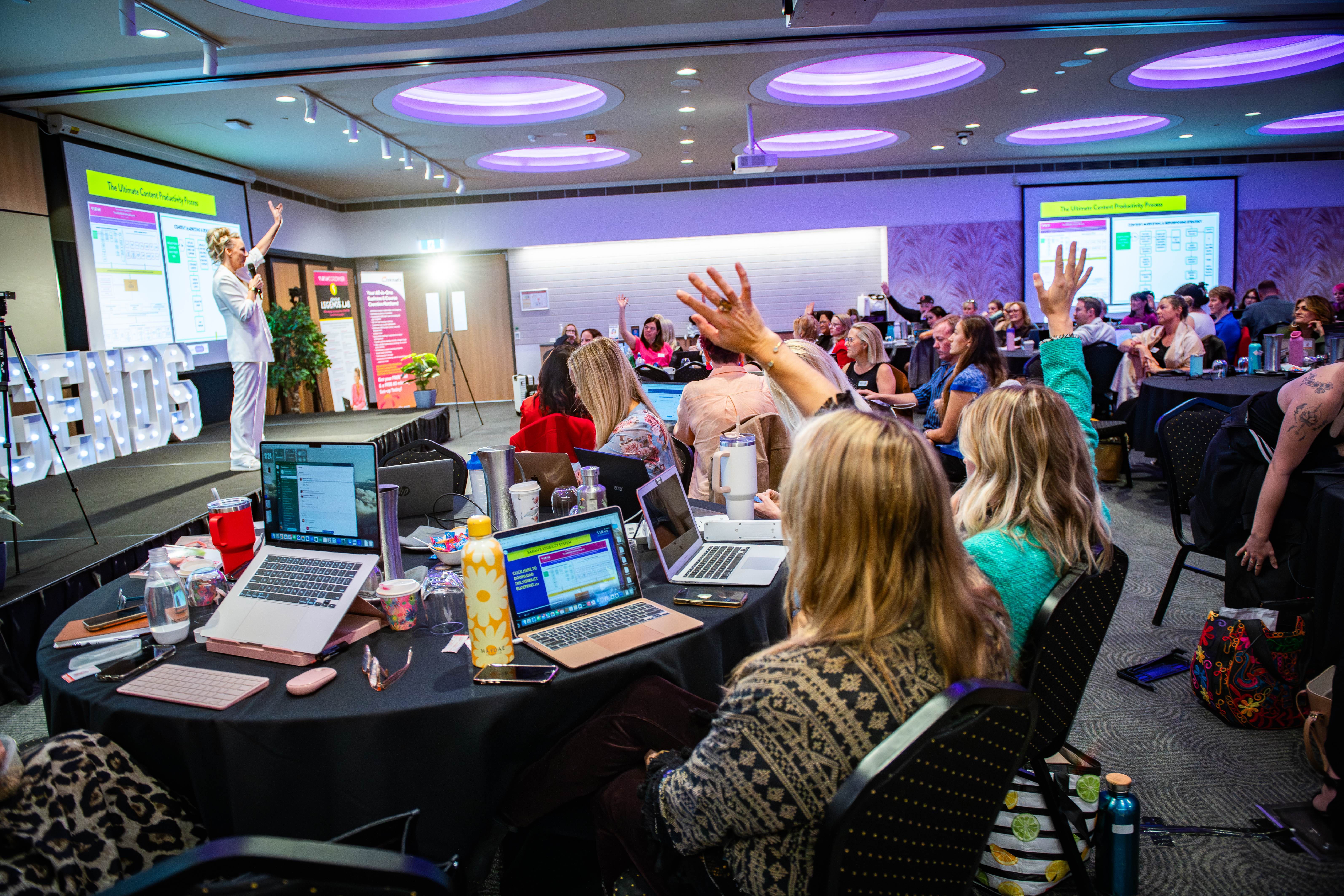 Workshop room full of laptops with hands raised