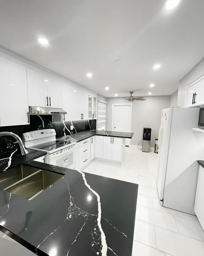 Open kitchen with black quartz counters, pot lights and white tile floor