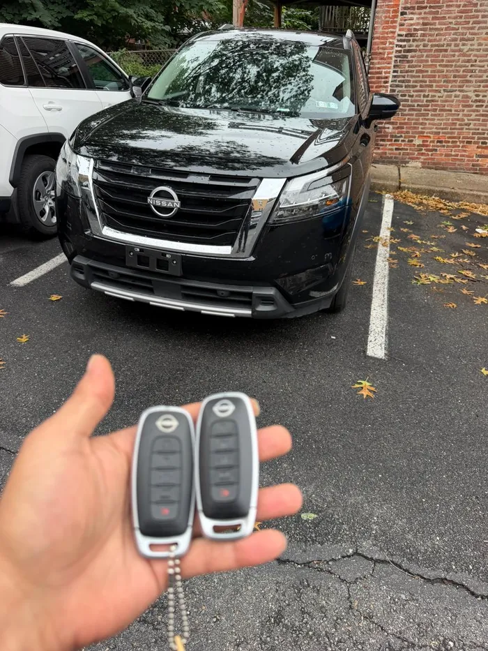Two new Nissan smart keys in front of a Nissan SUV