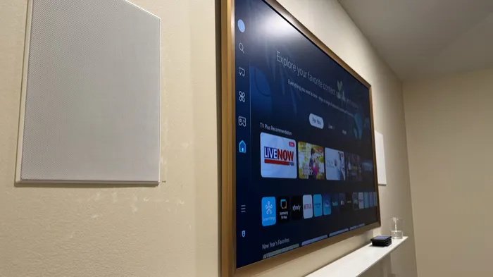 Samsung Frame TV with a wood bezel next to an in-wall speaker
