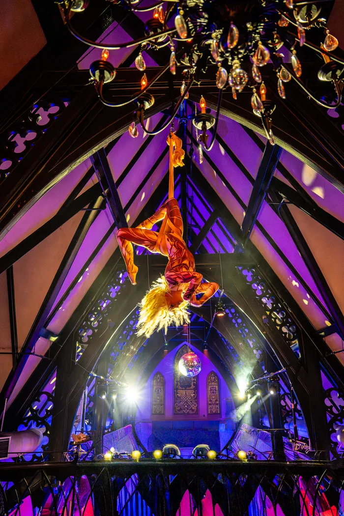 An aerialist performing above a gala crowd