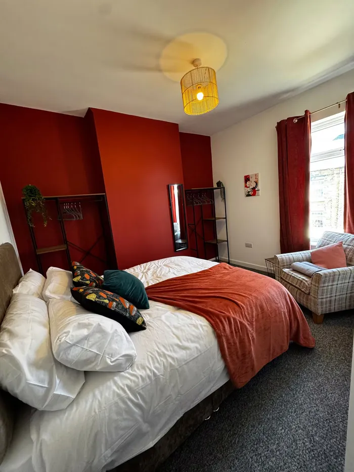 Double bedroom with red feature wall and orange throw at the Worsbrough home