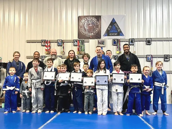 Kids and adult coaches together on the mat at a Delta Grappling Academy promotion day
