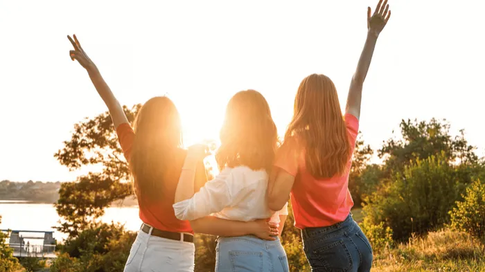 Three women celebrating outdoors at sunset