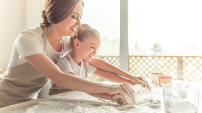 A mother and daughter kneading dough together