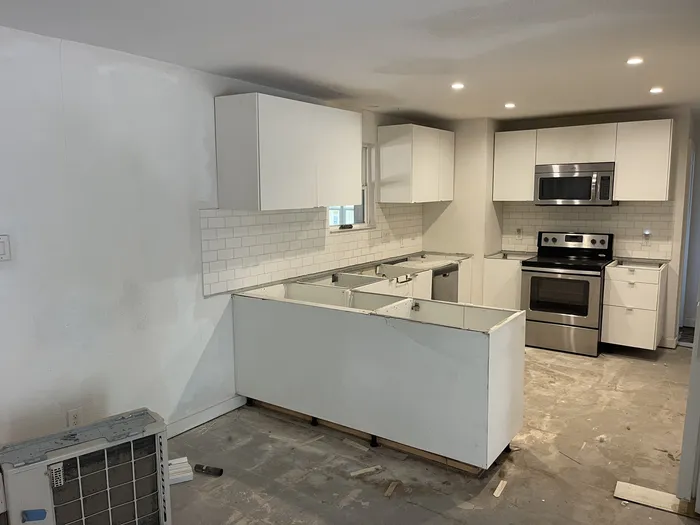 Kitchen mid-build: white cabinets set, counters and floors not yet finished