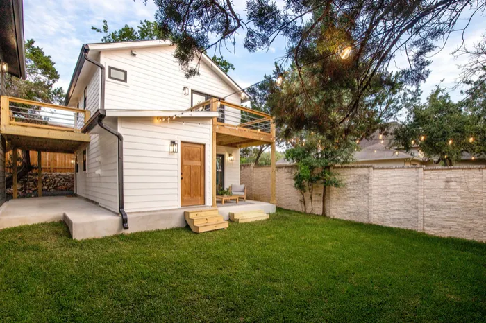 Two-story exterior in white lap siding with new decks and a stained wood door