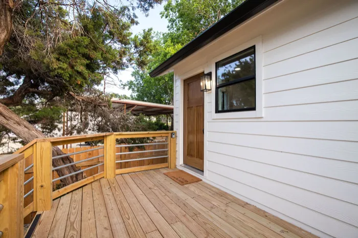 New wood deck with metal rail outside white lap siding