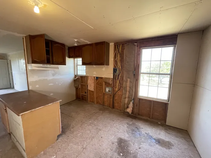 Kitchen before: torn-out walls, old cabinets and a stained subfloor