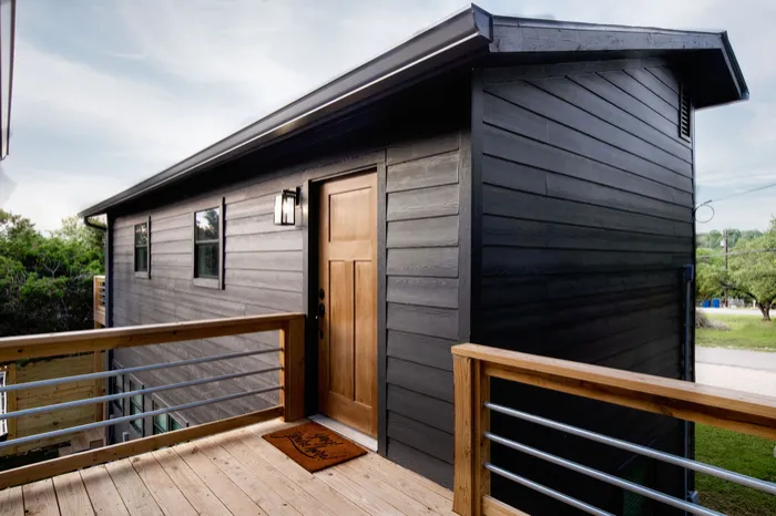 Dark lap siding, a stained wood door and a new deck with metal rail