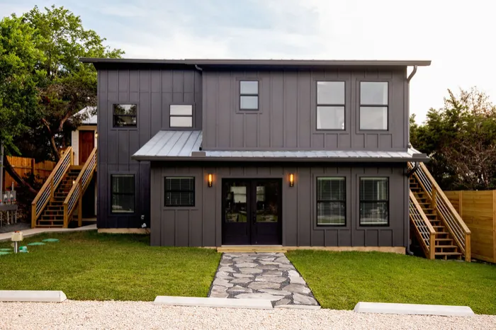 Two-story exterior refreshed in dark board and batten with new stairs and a stone path