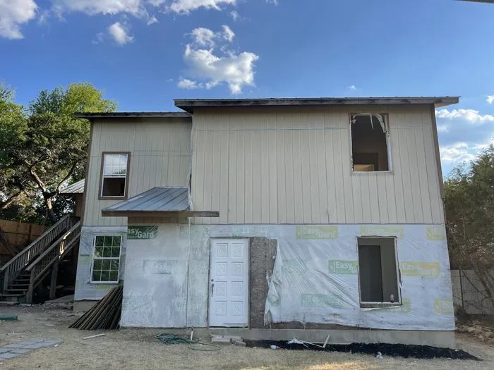 Two-story exterior before: house wrap, unfinished siding and open window frames