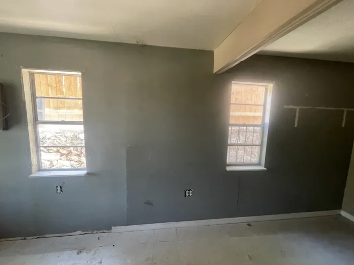 Room before: gray walls, bare subfloor and an exposed beam