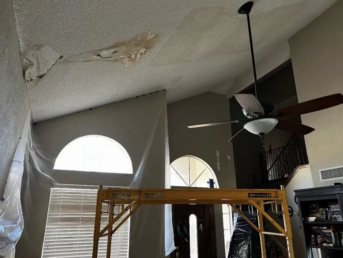 Popcorn ceiling being scraped in a living room with scaffolding